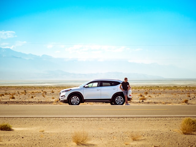 man standing next to broken down car
